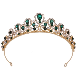 Detailed macro view of the gold tiara showing emerald teardrop stones and rhinestones