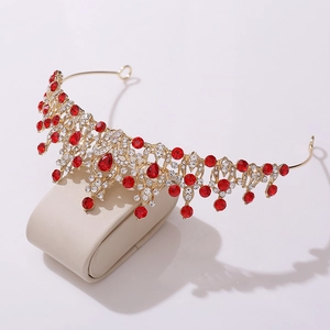 Detail view of gold bridal crown with red rhinestones and white crystals on a jewelry stand