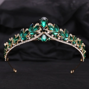 Detail shot of luxury gold bridal crown with deep green emerald stones on black velvet