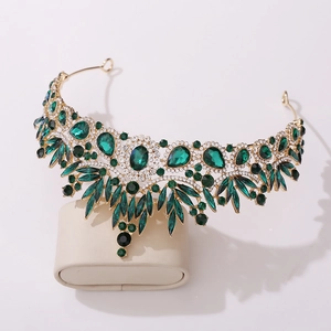 Baroque emerald crystal bridal crown with golden leaf accents on a jewelry display stand