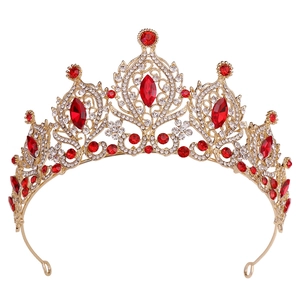 Détail d'une couronne de mariée dorée avec cristaux rouges et diamants sur fond blanc