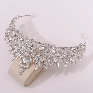 Close-up of silver baroque tiara with crystal leaves on a beige velvet display stand