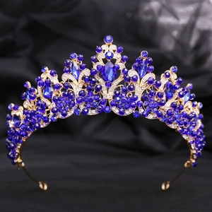 Detail of golden Baroque crown featuring deep blue crystals and intricate rhinestone leaf patterns