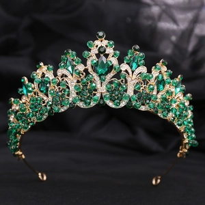 Macro view of gold baroque crown with emerald green crystals and white sparkling rhinestones