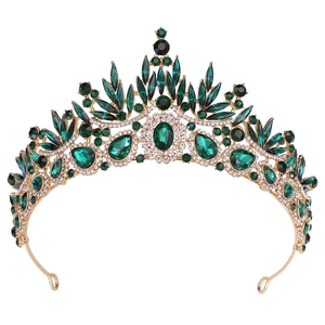 Detailed macro view of baroque gold crown with emerald water-drop crystals and white rhinestones
