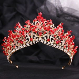 Close-up of golden bridal crown with red rhinestones and beads on black lace