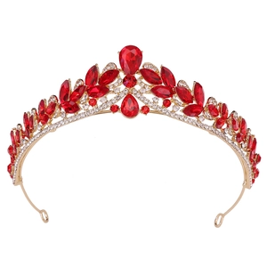 Close-up of golden bridal tiara featuring large red pear-shaped crystals and white rhinestones