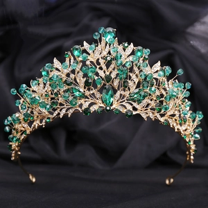 Détail macro d'une couronne de mariée dorée avec gemmes vert émeraude et cristaux blancs