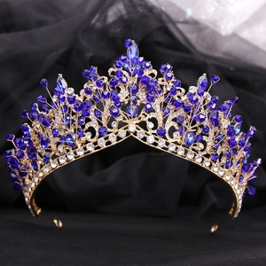 Close-up of golden bridal crown with blue gemstones and rhinestones on black tulle