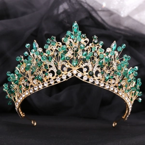 Detailed view of handmade gold bridal crown with deep green crystals and rhinestones