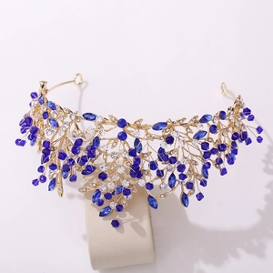 Macro detail of handmade bridal tiara featuring gold leaves and deep blue crystals