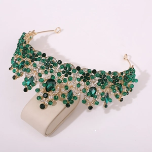 Close-up of Baroque gold crown featuring emerald green teardrop crystals and clear rhinestones