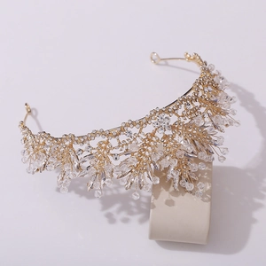 Détails d'une couronne de mariée dorée avec des grappes de cristal et feuilles de strass