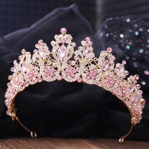 Macro detail of luxury gold bridal crown with pink crystals and intricate leaf patterns