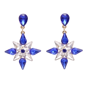 Macro view of crystal snowflake earrings featuring blue teardrop stones and gold settings