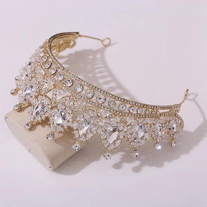Elegant gold bridal crown with crystal leaf patterns on a cream jewelry stand display