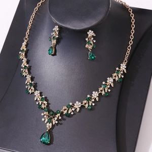 Detail of bridal jewelry set with green teardrop crystals and gold flower necklace