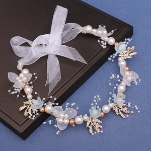 Close-up of handmade bridal headband with white pearls, blue petals, and gold metal leaves
