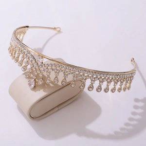 Detailed view of bridal gold crown with pear-cut rhinestones on jewelry display stand