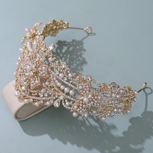Dettaglio di tiara nuziale dorata con filigrana floreale, perle bianche e cristalli