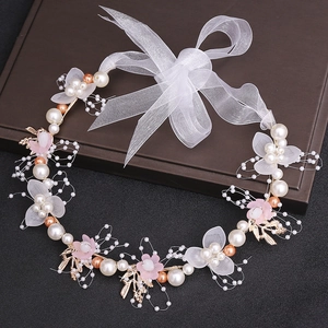 Detailed close-up of handmade bridal headband with pink flowers, pearls and golden leaves