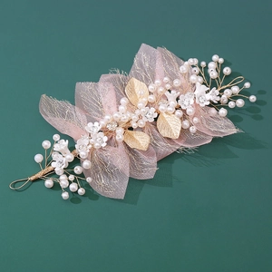 Close-up of handmade floral hairpiece with pink tulle, pearls and golden leaves