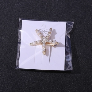 Detailed shot of starfish bridal hair clip with pearls and rhinestones in OPP packaging