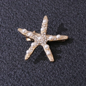 Close-up of golden starfish hair clip with white faux pearls and sparkling rhinestones