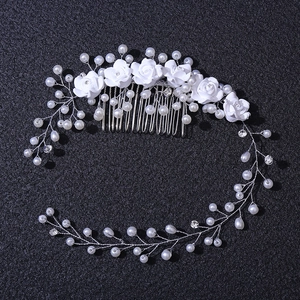Detail of handmade bridal hair comb with white resin flowers and pearl vine decoration