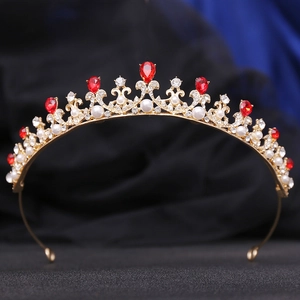 Detail of a vintage golden princess crown with red teardrop stones and pearls