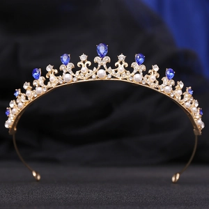 Detailed close-up of golden crown with blue teardrop crystals and white pearls decoration
