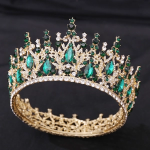 Close-up of gold baroque crown with emerald green crystals and sparkling diamonds