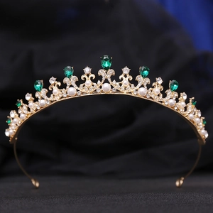 Detailed view of a gold princess crown with green gemstones and white pearls on velvet