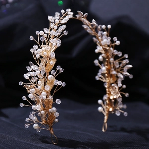 Close-up of handmade bridal headband with gold leaves, white pearls and crystals