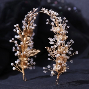Detail view of handmade bridal leaf hairpiece with pearls and crystals on dark fabric