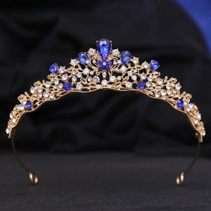 Detailed close-up of golden Baroque crown with deep blue crystals and fine white rhinestones