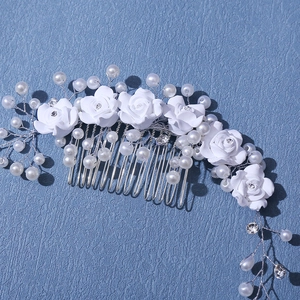 Close-up of bridal hair comb with white handmade ceramic flowers and sparkling rhinestones
