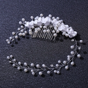 Close-up of white roses and pearls on a silver bridal hair comb with rhinestone accents