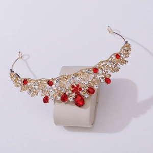 Detail of baroque gold crown with intricate floral metalwork and red teardrop gems