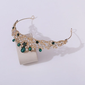 Detail of baroque gold tiara featuring emerald green crystals and white rhinestones