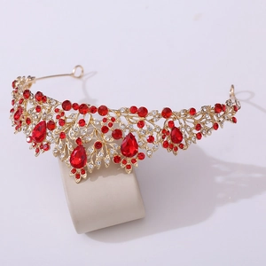 Detail of golden baroque crown with red water-drop rhinestones and hollow floral patterns