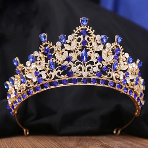 Macro detail of luxury gold bridal crown featuring deep blue teardrop gems and crystals