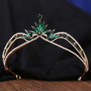 Detailed close-up of golden bridal tiara with green marquise gems and white rhinestones