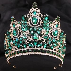 Exquisite gold crown detailing with emerald pear-cut crystals on dark velvet background