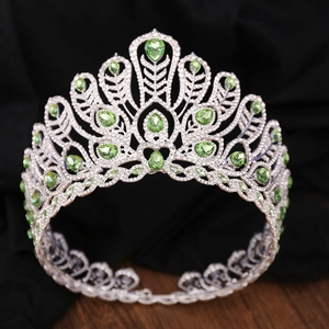 Gros plan du diadème argenté avec cristaux verts et strass sur tissu noir plissé