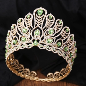 Détail d'une couronne dorée avec gemmes vertes et cristaux sur velours noir