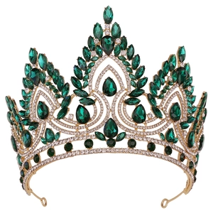 Close-up of golden Baroque crown with green teardrop gems and sparkling white crystals