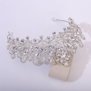 Detailed view of silver bridal crown with crystals and pearls on jewelry stand