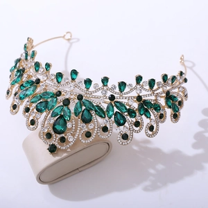 Détail d'une couronne de mariée dorée avec des gemmes vert émeraude et cristaux brillants