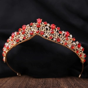 Detalle de tiara nupcial dorada con piedras rojas de gota y cristales de circonita